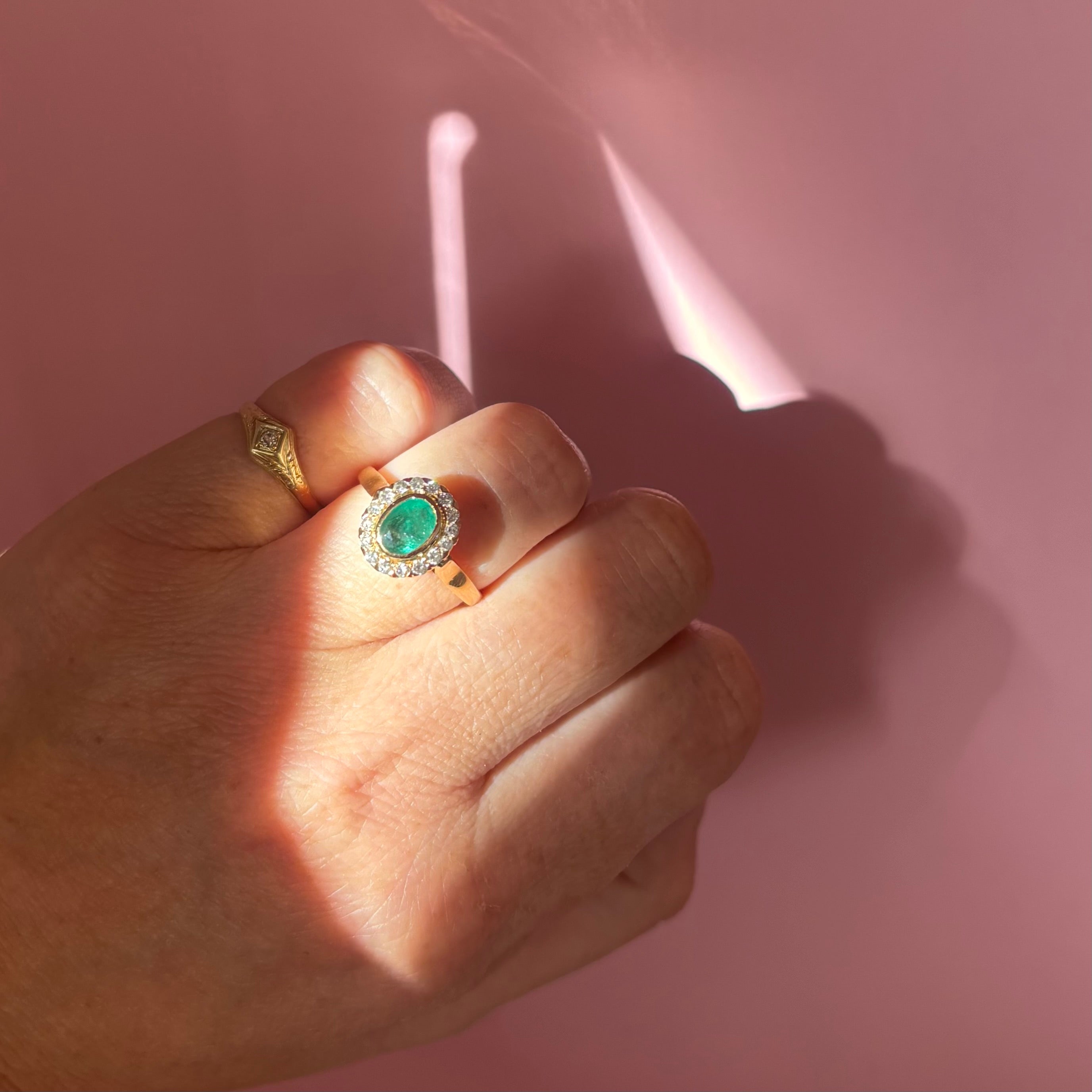 18ct gold bezel set, oval emerald and diamond cluster ring