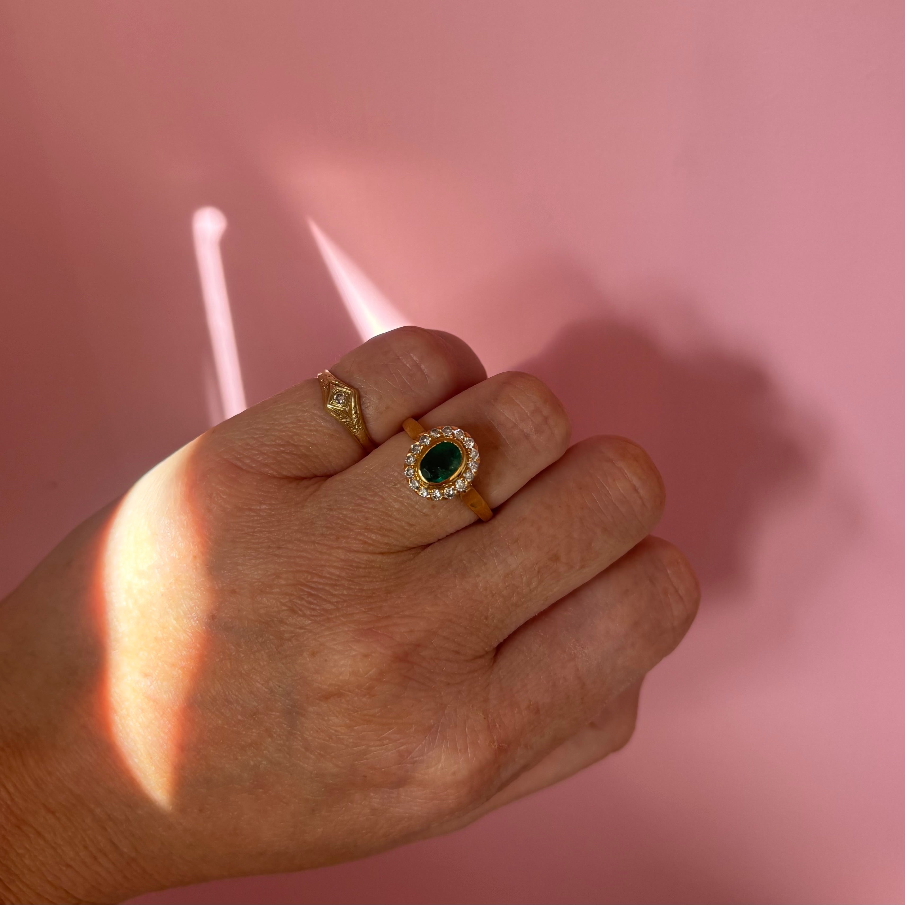 18ct gold bezel set, oval emerald and diamond cluster ring