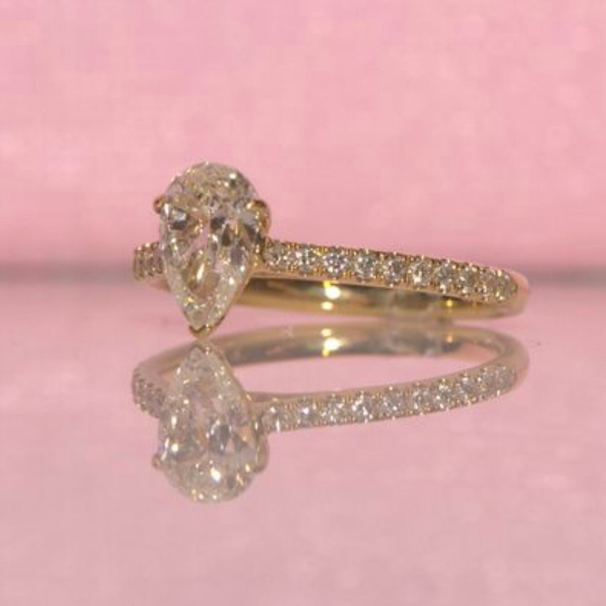 18ct yellow gold 1.0ct pear shaped diamond ring on a diamond half eternity band