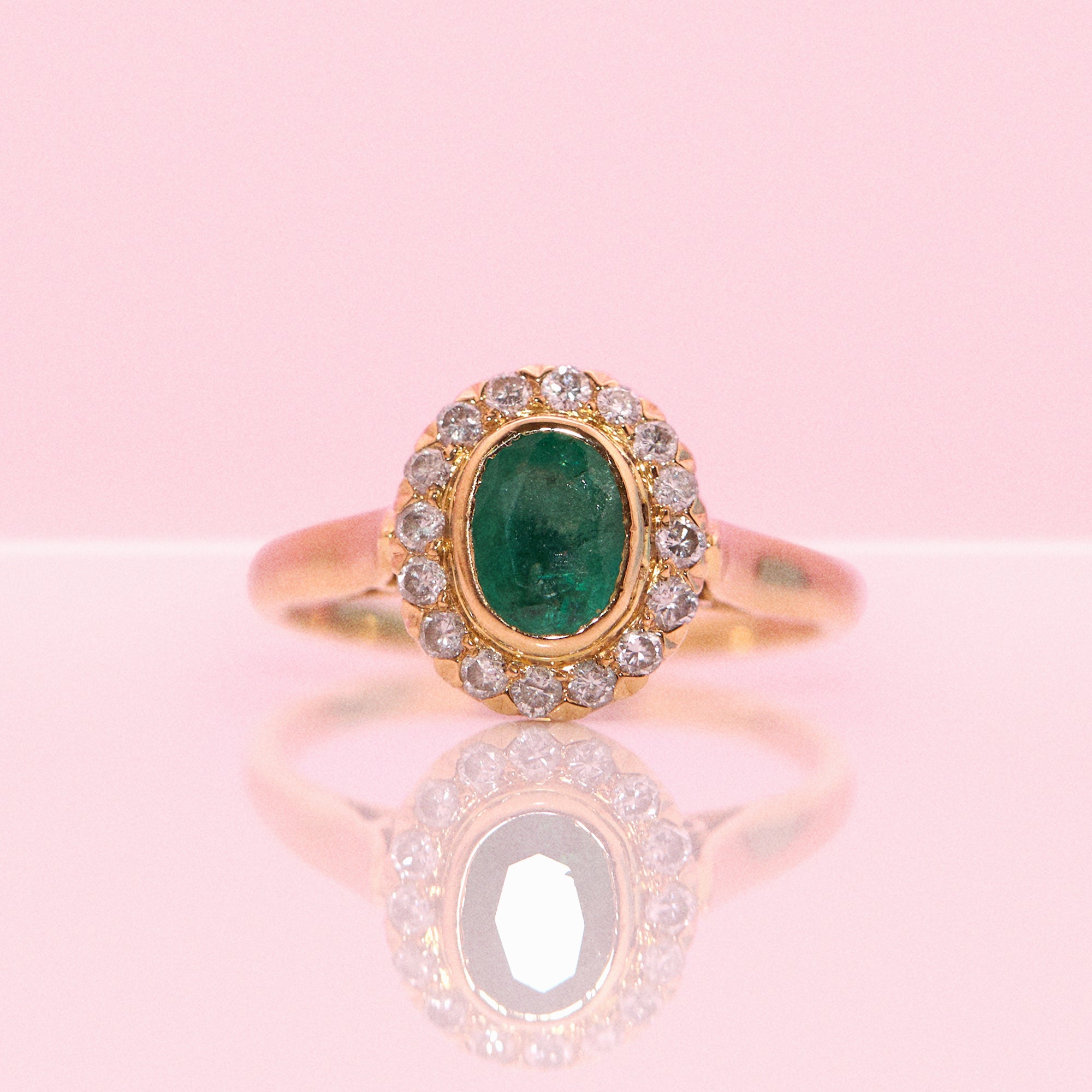 18ct gold bezel set, oval emerald and diamond cluster ring