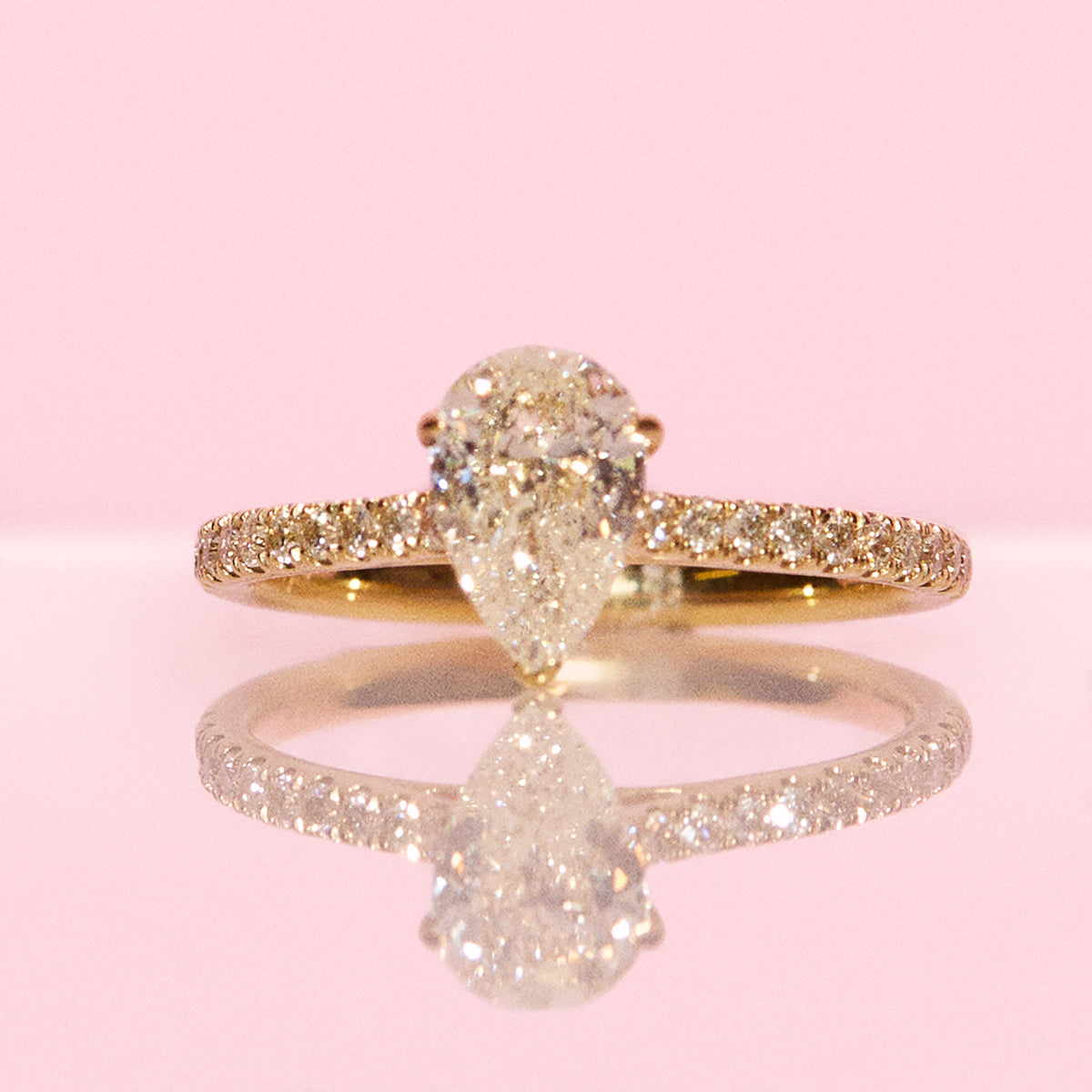 18ct yellow gold 1.0ct pear shaped diamond ring on a diamond half eternity band
