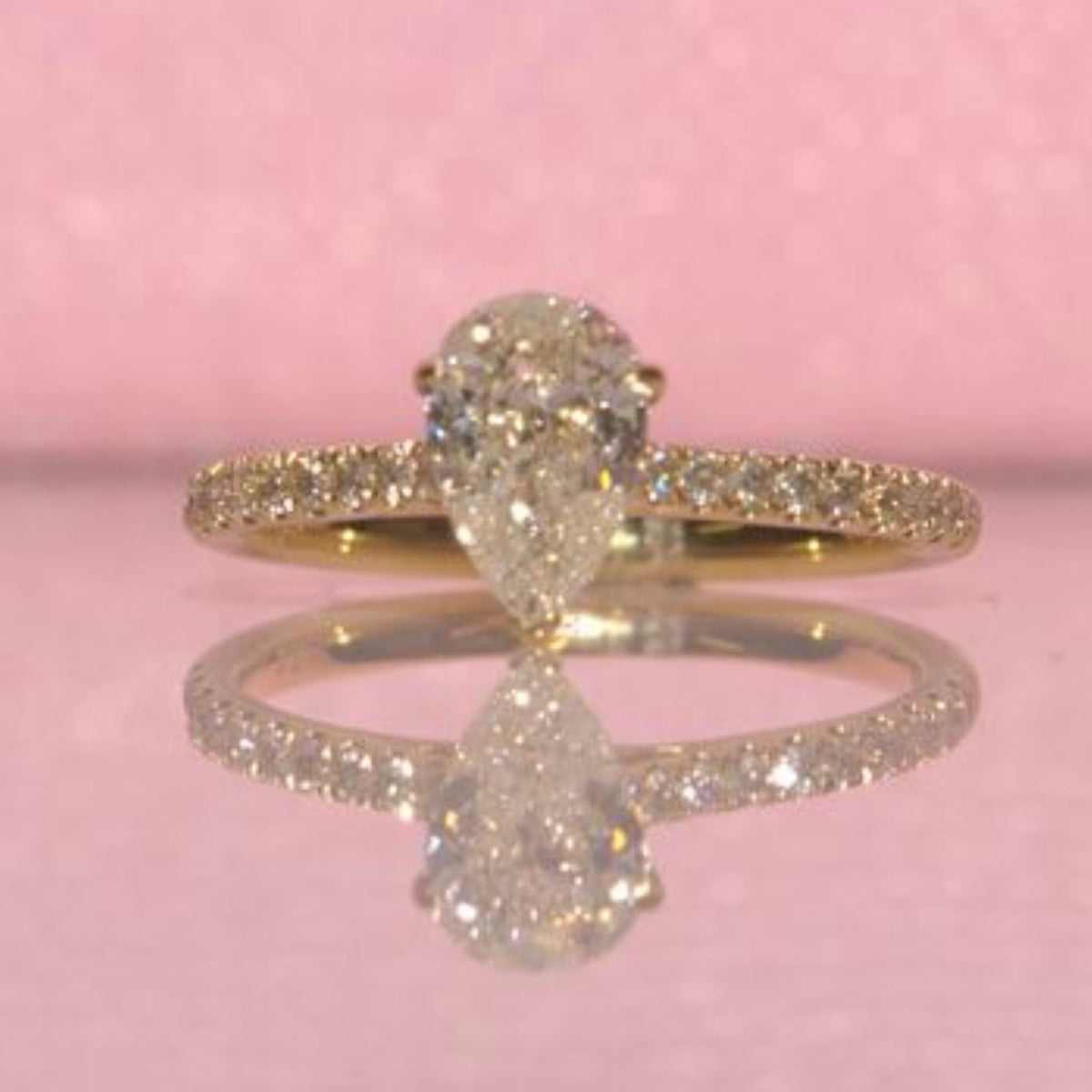 18ct yellow gold 1.0ct pear shaped diamond ring on a diamond half eternity band