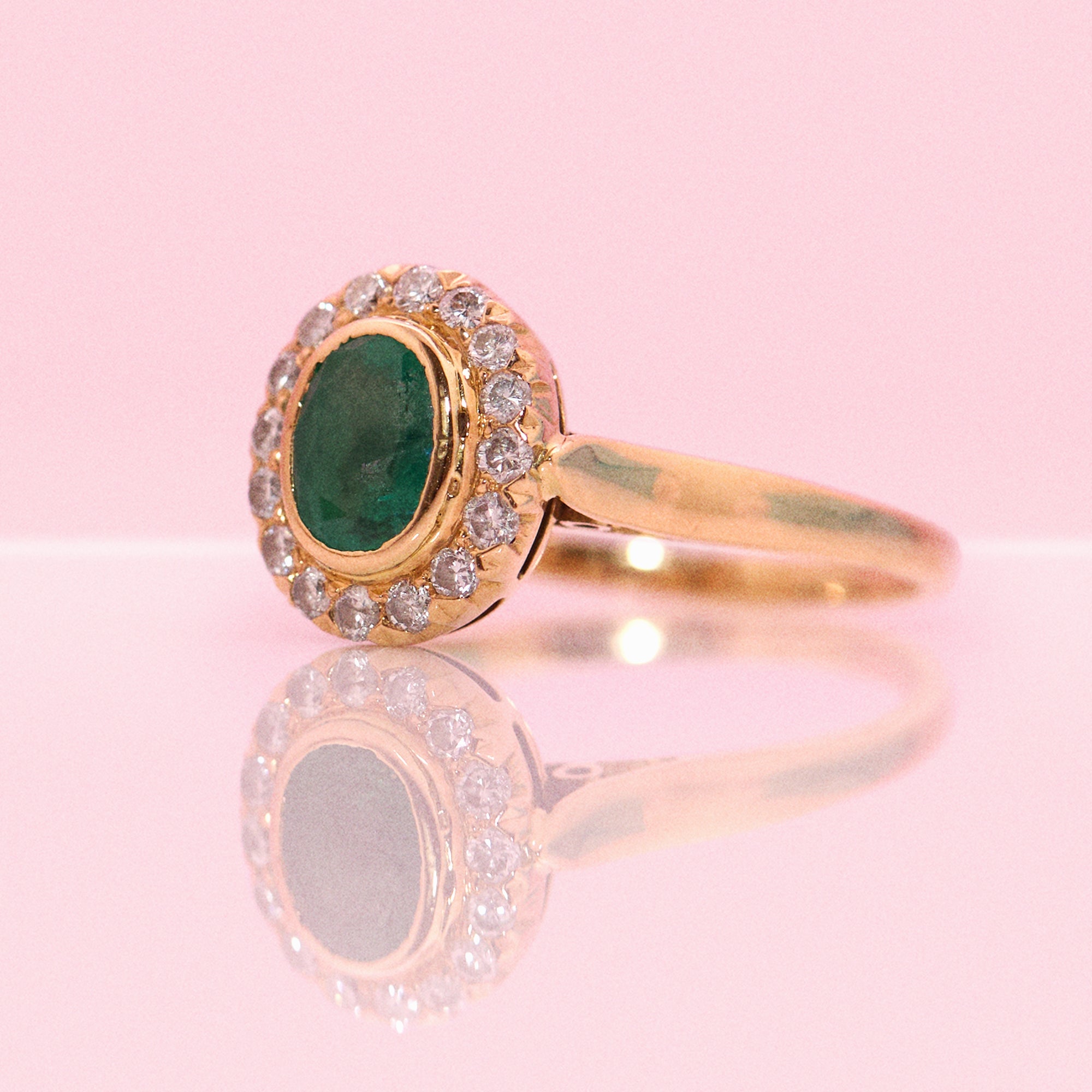 18ct gold bezel set, oval emerald and diamond cluster ring